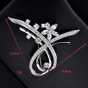 Gros plan d'une broche fleur en zircon argenté, dimensions 5,4cm x 4,4cm sur fond noir