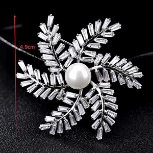 Détail de la broche argentée de 4,9 cm avec zircons, forme florale et perle blanche