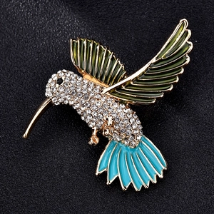 Detail of hummingbird brooch with emerald green enamel wings and white rhinestones