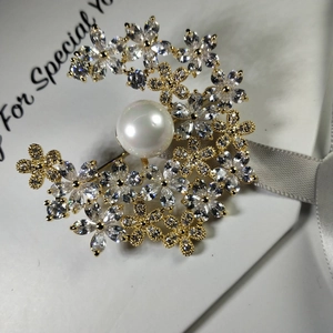 Detail van de halve maanvormige broche met zirkonia-bloemen en een witte parel