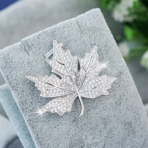 Luxurious maple leaf brooch with silver plating and clear cubic zirconia on jewelry stand