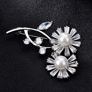 Detailed view of silver floral brooch with white pearls and baguette cut zirconia