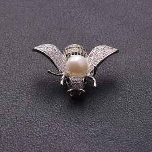 Detail der Bienenbrosche mit weißer Perle und Mikropavé-Kristallen auf schwarzem Leder