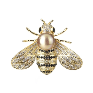 Broche abeille dorée raffinée avec cristaux de zircon et perle sur fond blanc uni
