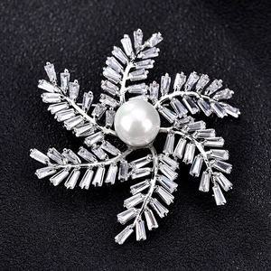 Vue macro d'une broche moulin argentée avec zircons et centre en perle blanche