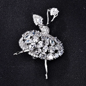 Détail de la broche ballerine argentée ornée de zircons scintillants sur fond noir soyeux