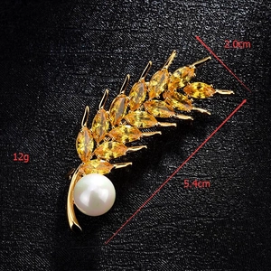Detail view of wheat ear brooch with yellow crystals and large pearl on golden metal base