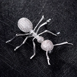 Detailed view of silver ant brooch encrusted with sparkling zircon stones on black background