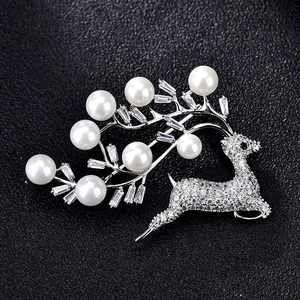 Broche renne élégante en argent avec zircons blancs et perles sur fond noir texturé