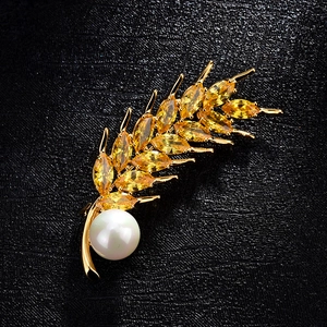 Elegant gold wheat brooch with yellow crystal stones and a white pearl on black leather