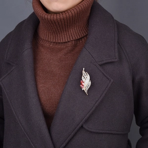 Elegant gold leaf brooch with white crystals and red gems on a dark coat lapel