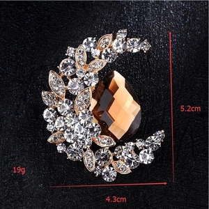Detailed macro view of moon-shaped golden brooch with crystals and amber gemstone