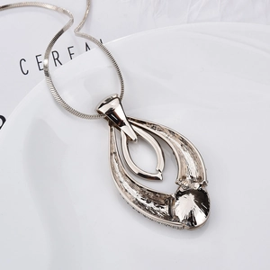 Detailed close-up of a silver teardrop pendant with micro-pave crystals on a white ceramic plate