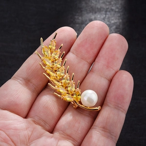 Close-up of golden wheat brooch with yellow crystals and a white round pearl
