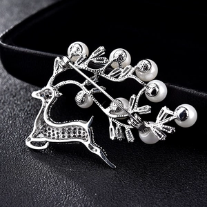 Broche cerf en argent avec perles blanches et fermoir à épingle sur fond texturé noir