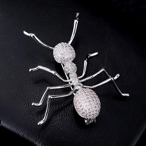 Macro shot of silver ant brooch with full zircon stones on black leather background