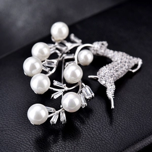 Vue macro d'une broche cerf avec perles blanches et zircons sur cuir noir texturé
