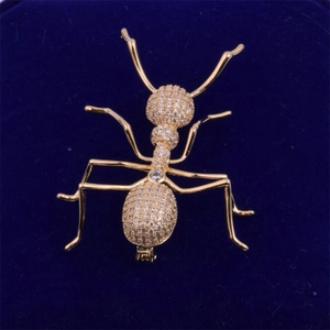 Elegant gold-tone ant brooch with sparkling zircons set on a dark blue velvet background
