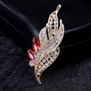 Elegant gold leaf brooch with sparkling crystals and red marquise-cut gems on black box