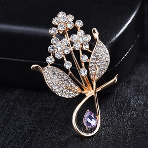 Elegant gold flower brooch with white crystal petals and a purple pear-shaped gemstone
