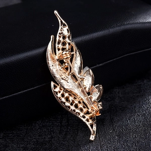 Detailed back view of a golden feather brooch with textured metal and secure pin clasp