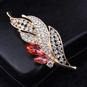 Elegant gold leaf brooch with red gemstones and white crystals on black leather