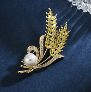 Elegant gold wheat ear brooch with yellow crystals and white pearl on blue velvet