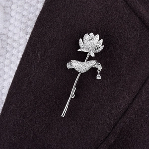 Détail macro d'une broche lotus argentée avec zircons étincelants et pendentif goutte