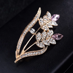 Macro detail of golden wheat brooch with sparkling white rhinestones and pink marquise stones