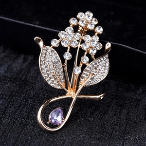 Elegant gold flower brooch with white diamonds and a purple teardrop crystal pendant