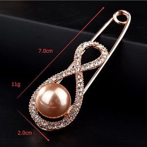 Détail d'une broche infinie dorée avec perle champagne et dimensions du produit