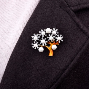 Elegante spilla ad albero dorata con perle bianche e zirconi su un cappotto nero