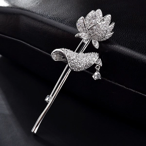Vue macro de la broche lotus en argent avec zircons sur fond de cuir noir texturé