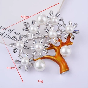 Dettaglio della spilla albero della fortuna con smalto arancione, perle e zirconi