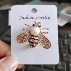 Détail d'une broche abeille avec perle d'imitation blanche et ailes en strass brillants
