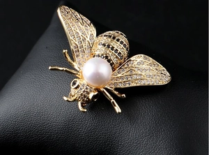 Macro de broche abeille avec grande perle blanche et zircons sur cuir noir