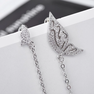 Détail macro de boucles d'oreilles ailes de papillon en argent avec zircons et longs glands