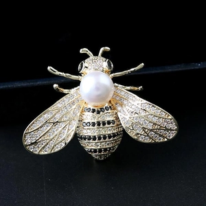 Vue détaillée d'une broche abeille avec perle blanche, dorure et zircons scintillants