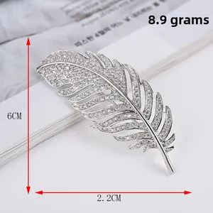 Macro detail of silver feather brooch showing zircon inlay and 6cm size measurement