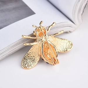 Détail du dos de la broche abeille dorée montrant le fermoir épingle et la texture des ailes