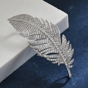 Macro shot of silver feather brooch with shimmering cubic zirconia on blue velvet
