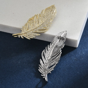 Detail view of gold and silver feather brooches with zircon inlay and back pin closure