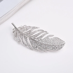 Macro shot of silver feather brooch with sparkling cubic zirconia on a white background