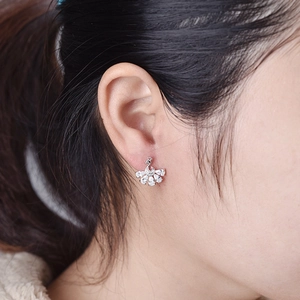 Detailed close-up of a silver peacock stud earring with sparkling zircon stones on ear