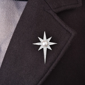 Detail of a sparkling star brooch with a white pearl on a brown wool blazer lapel