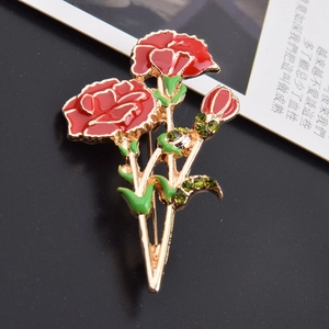 Macro shot of red enamel carnation brooch with green crystal rhinestones on gold base