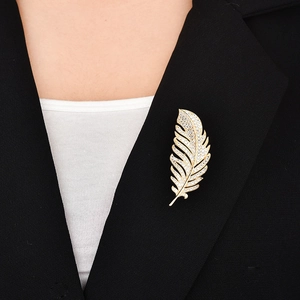 Detail of elegant gold feather brooch with pavé zircons on a black suit lapel
