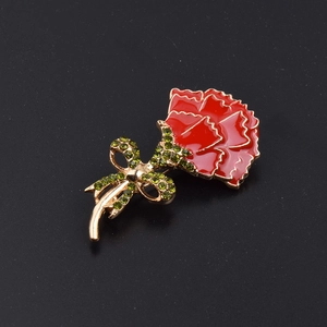 Detail of red enamel carnation brooch with green rhinestones on gold metal base