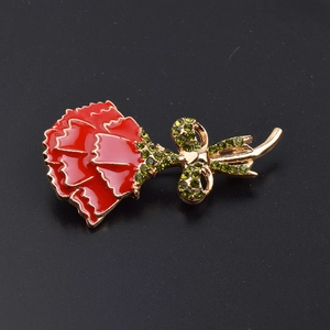 Macro detail of enamel carnation brooch with green crystals and gold-plated stem