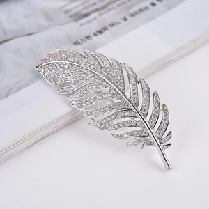 Detail of silver feather brooch with sparkling zircons against a fashion magazine